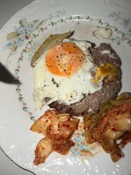 Fried egg over seared beef steak with kimchi, pickled vegetables, floral po.. Stock Photos