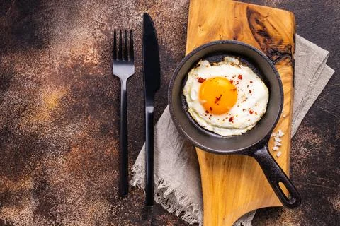 Fried egg in the pan on a dark rustic background. Stock Photos
