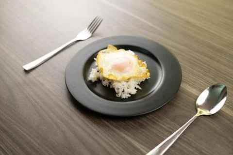 Fried egg placed on white rice in a black dish Stock Photos