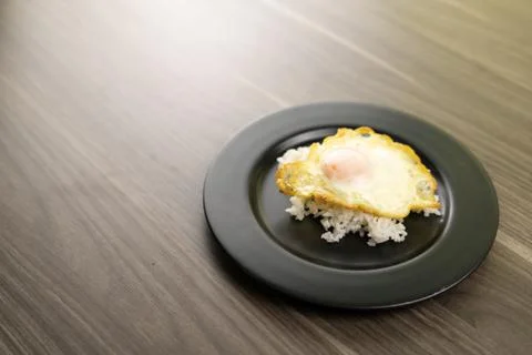 Fried egg placed on white rice in a black plate in the right . Stock Photos