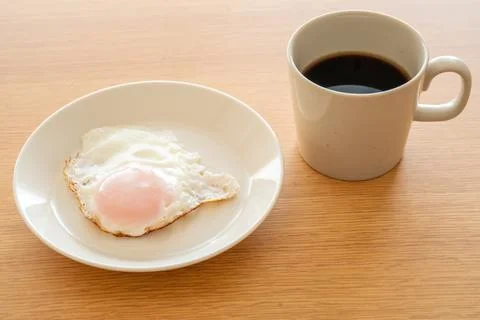 A fried egg on a plate and a cup of coffee Stock Photos
