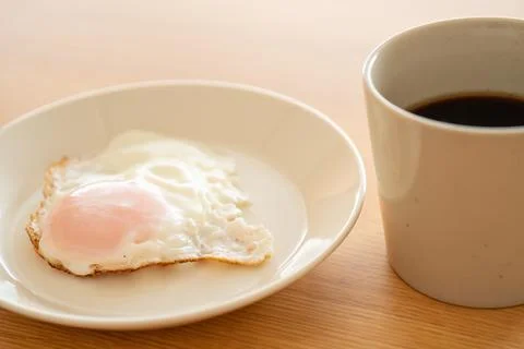 A fried egg on a plate and a cup of coffee Stock Photos