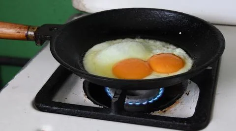 Fried egg preparation for breakfast at rustic kitchen Stock Photos