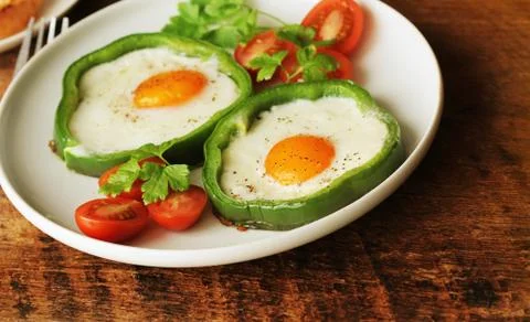 Fried egg in the ring of the bell peppers with herbs Stock Photos