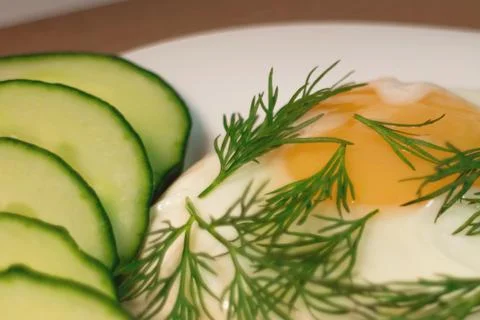 Fried egg serving slices of cucumber Stock Photos