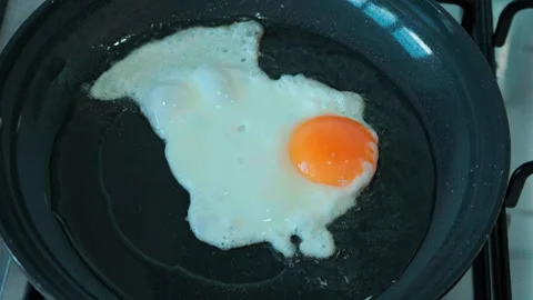 Fried egg sizzles gently in black skillet Stock Footage 337653829