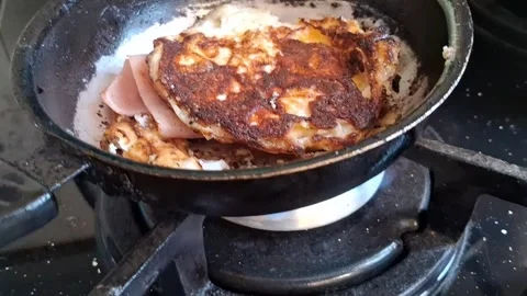 Fried egg with sliced ham cooking in pan motion video clip Stock Footage 338134636