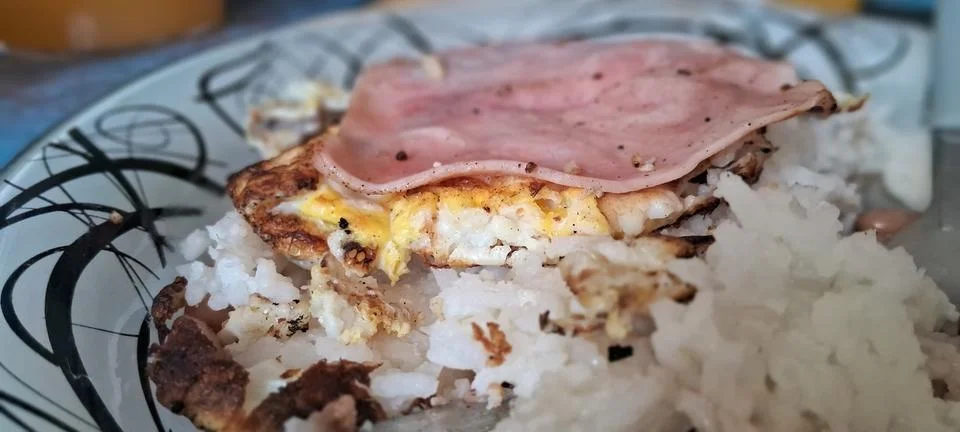 Fried egg with sliced ham served over fluffy white rice Stock Photos