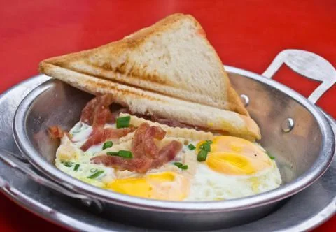Fried egg in a small pan on red table Stock Photos