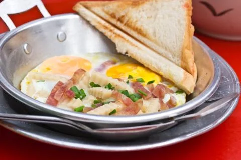Fried egg in a small pan on red table Stock Photos