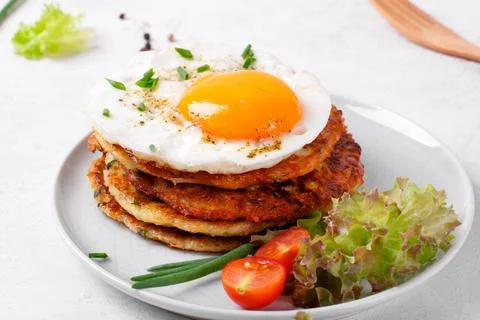 Fried egg on the stack of zucchini fritters Stock-Fotos