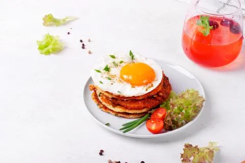 Fried egg on the stack of zucchini fritters and berry lemonade Stock Photos