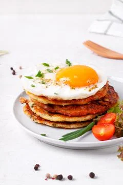 Fried egg on the stack of zucchini fritters Stock Photos