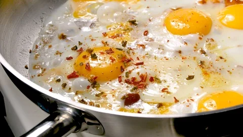 Fried egg sunny side up in a pan. Sprinkled with spices Stock Footage 122834491