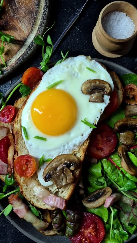 Fried egg on toast bread with bacon, tomatoes and lettuce Stock Footage 305064617