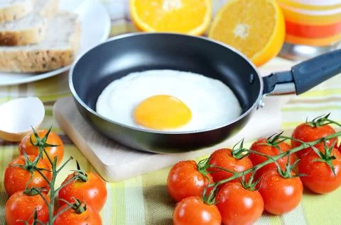Fried egg, toast bread, fresh juice, tomatoes and oranges Stock Photos