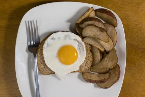 Fried egg on wheat  bread with a side of potato wedges Stock Photos
