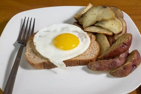 Fried egg on wheat  bread with a side of potato wedges Stock Photos