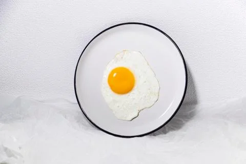 Fried egg on a white plate in a white background. Trendy food. Stock Photos