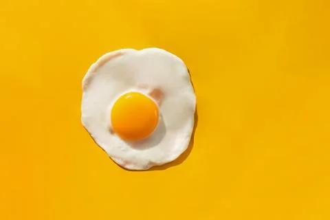 Fried egg on yellow background Stock Photos
