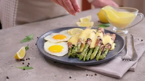 Fried eggs and freshly cooked asparagus wrapped with bacon on a plate Vídeos de archivo 218222351
