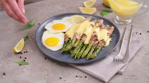 Fried eggs and freshly cooked asparagus wrapped with bacon on a plate Vídeos de archivo 218222648
