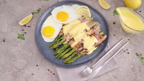 Fried eggs and freshly cooked asparagus wrapped with bacon on a plate Vídeos de archivo 218222659