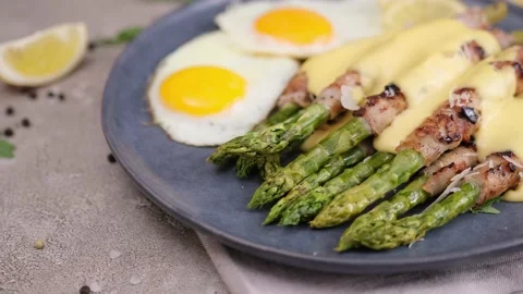 Fried eggs and freshly cooked asparagus wrapped with bacon on a plate Vídeos de archivo 218222758