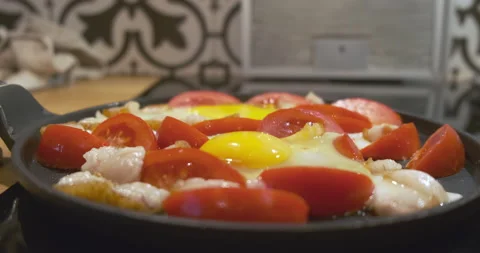 Fried eggs are fried in a black flat frying pan. Side view, close-up. Yellow Stock Footage 210152948