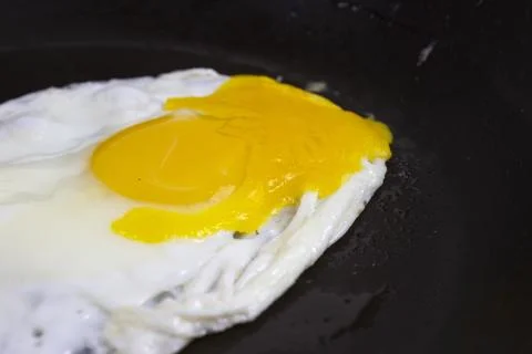 Fried eggs are fried in a black oily pan Stock Photos