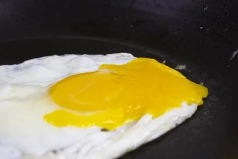 Fried eggs are fried in a black oily pan Stock Photos