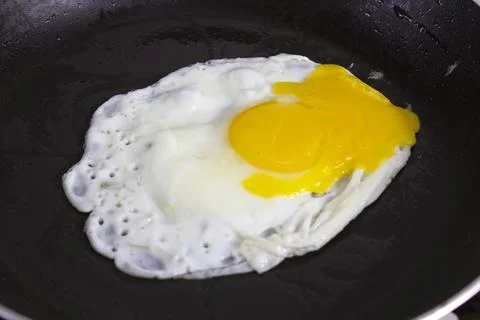 Fried eggs are fried in a black oily pan Stock Photos