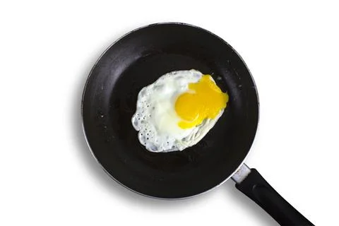 Fried eggs are fried in a black oily pan in isolated white background Stock Photos