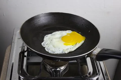 Fried eggs are fried in a black oily pan Stock Photos
