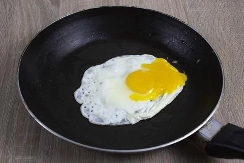 Fried eggs are fried in a black oily pan Stock Photos