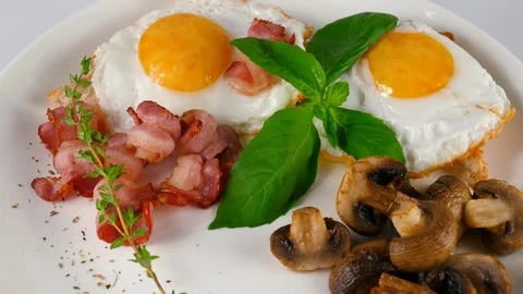 Fried eggs with bacon and sliced mushrooms, often dish on a breakfast Stock Footage 87404388
