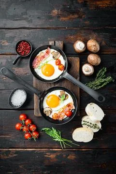 Fried eggs with bacon and vegetables in cast iron frying pan, on old dark woo Foto stock