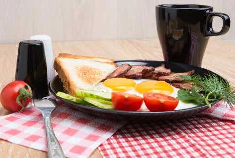 Fried eggs with bacon on black dish Stock Photos