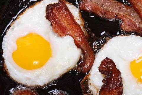 Fried eggs with bacon in a pan close-up. top view Stock Photos