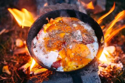 Fried eggs with bacon in a pan in the forest. Food at the camp. Scrambled egg Stock Photos