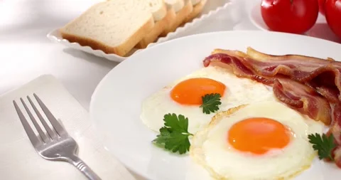 Fried eggs with bacon on a plate. breakfast with fresh vegetables and bread. Stock Footage 242491948