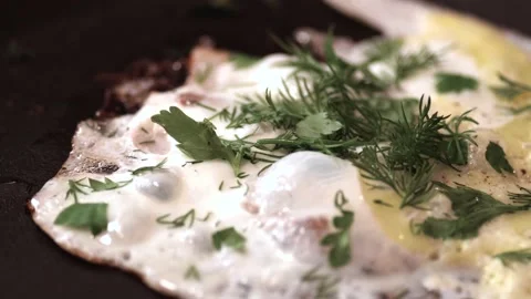 Fried eggs with bacon slices and herbs are fried on the stove. Close-up wiring Stock Footage 146335982