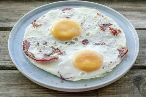 Fried eggs with bacon on the table for breakfast Stock Photos
