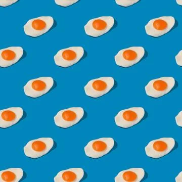 Fried eggs on blue seamless pattern. Stock Photos
