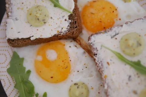 Fried eggs with bread,  sauce, and salad greens, close up Stock Photos