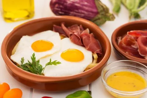Fried eggs in a ceramic cup with spanish jamon for breakfast on a white backg 스톡 사진
