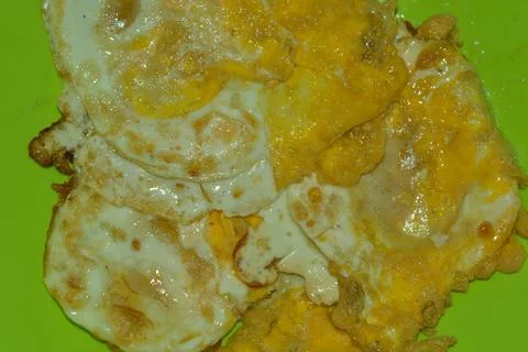 Fried eggs with crispy edges on green plate Stock Photos