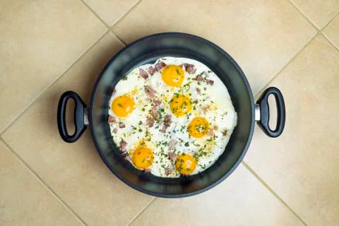 Fried eggs in a deep frying pan with bacon. Stock Photos
