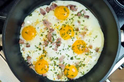 Fried eggs in a deep frying pan with bacon. Stock Photos