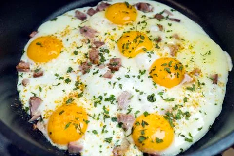 Fried eggs in a deep frying pan with bacon. Stock Photos